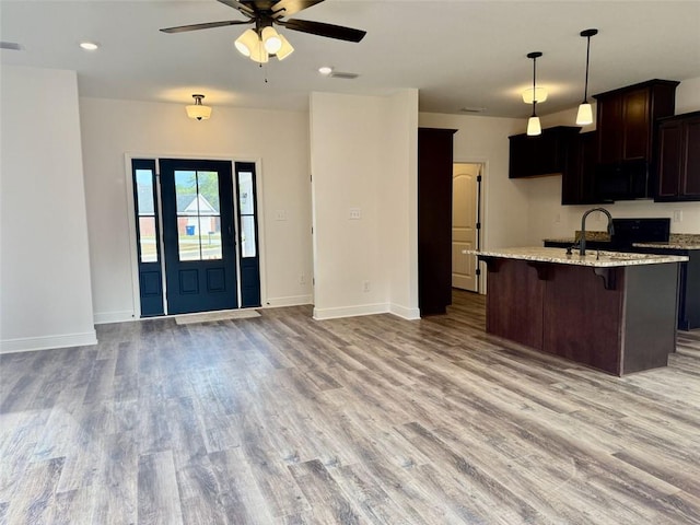 kitchen featuring open floor plan, a sink, an island with sink, and light wood finished floors