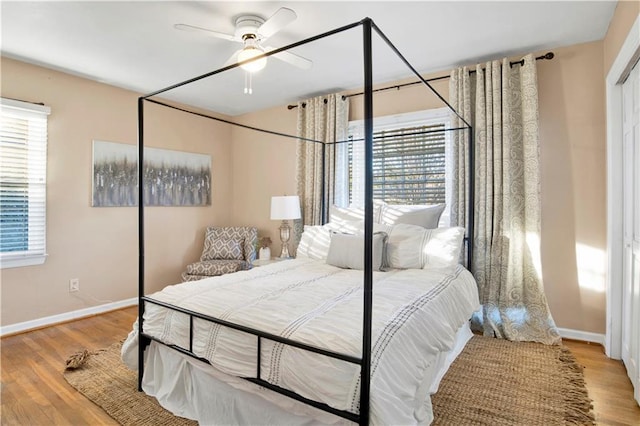 bedroom featuring ceiling fan, light wood-type flooring, and multiple windows