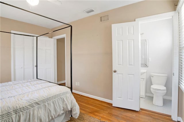 bedroom featuring a closet, ensuite bathroom, and light hardwood / wood-style flooring