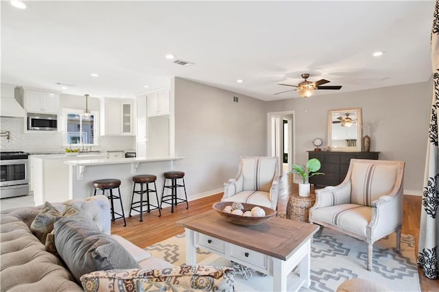 living room with ceiling fan and light wood-type flooring