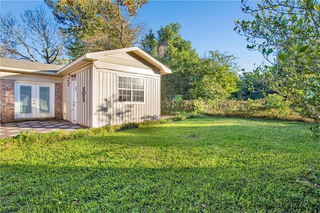 view of outdoor structure with a lawn and french doors