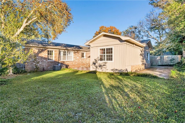 back of house with central AC unit and a lawn