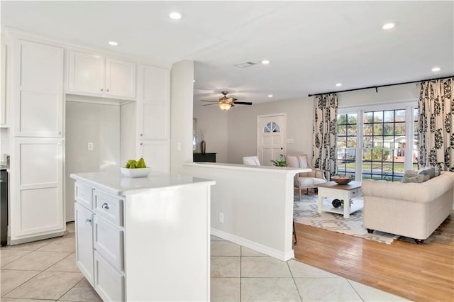 kitchen with light wood-type flooring, white cabinetry, ceiling fan, and a kitchen island