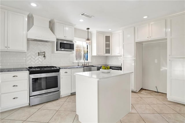 kitchen featuring white cabinets, custom exhaust hood, light tile patterned floors, and appliances with stainless steel finishes