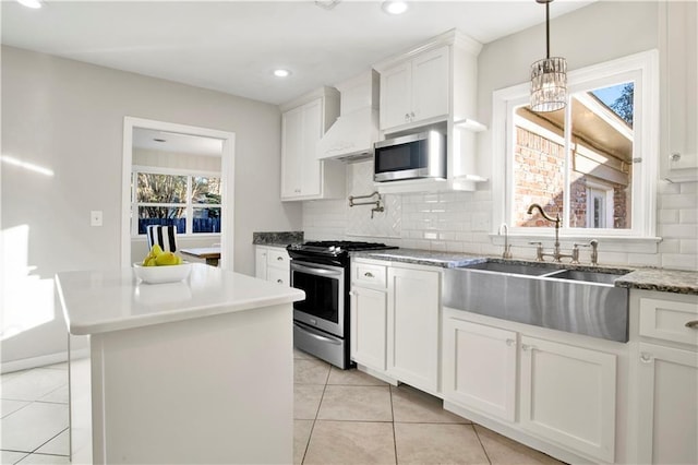 kitchen featuring decorative backsplash, appliances with stainless steel finishes, custom range hood, white cabinets, and a center island