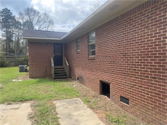 view of side of property with entry steps, central AC unit, brick siding, and crawl space