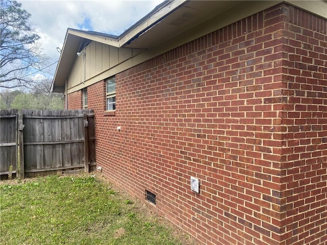 view of home's exterior featuring crawl space, brick siding, and fence