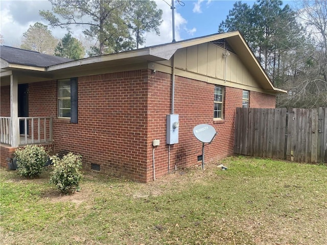 view of property exterior featuring crawl space, board and batten siding, brick siding, and fence