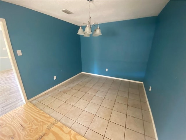 unfurnished room with a chandelier, visible vents, and baseboards