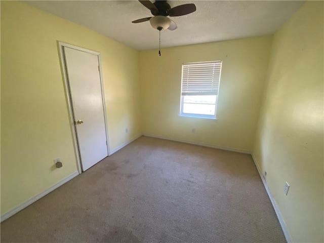 carpeted spare room featuring baseboards and ceiling fan