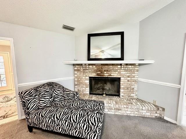 living room with visible vents, a textured ceiling, a brick fireplace, and carpet flooring