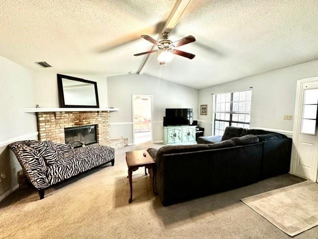 carpeted living area featuring visible vents, a brick fireplace, vaulted ceiling with beams, a textured ceiling, and a ceiling fan