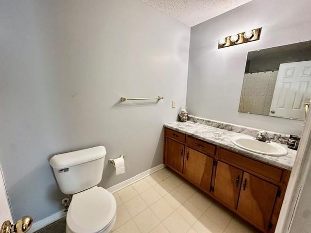 bathroom with vanity, toilet, baseboards, and a textured ceiling