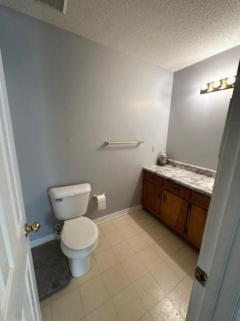 half bath featuring baseboards, toilet, vanity, and a textured ceiling