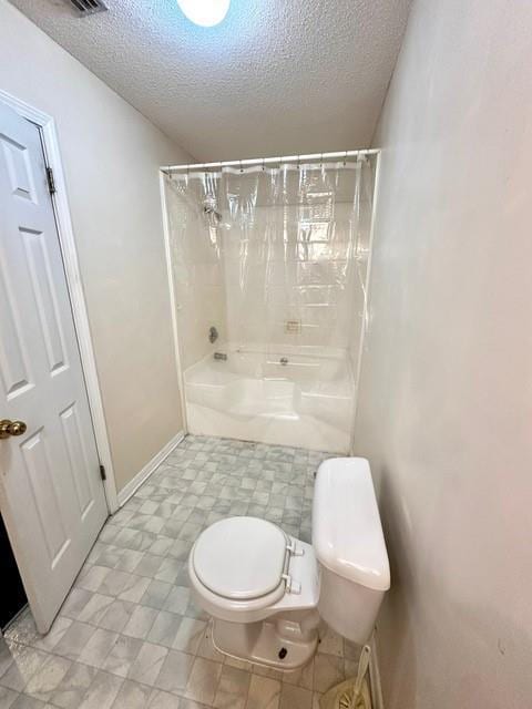 bathroom with baseboards, toilet, shower / washtub combination, and a textured ceiling