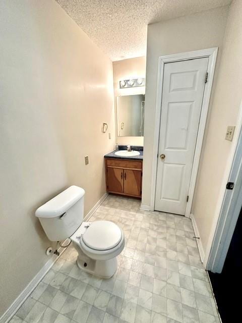 bathroom featuring vanity, toilet, baseboards, and a textured ceiling