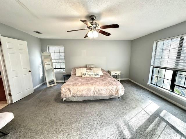 carpeted bedroom featuring visible vents, baseboards, a textured ceiling, and a ceiling fan