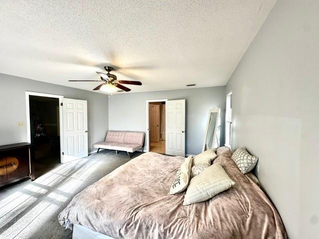 bedroom with visible vents, ceiling fan, a textured ceiling, and carpet