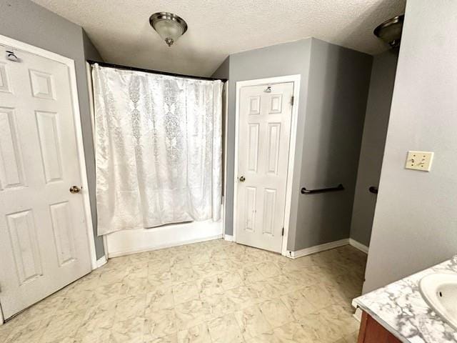 full bathroom with baseboards, a shower with curtain, vanity, and a textured ceiling