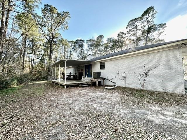 back of property featuring a deck, central AC unit, and brick siding