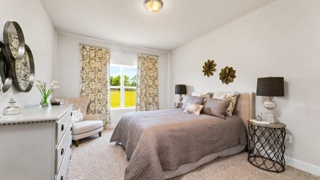 bedroom with baseboards, light colored carpet, and lofted ceiling