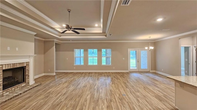 unfurnished living room featuring baseboards, visible vents, a fireplace, ceiling fan with notable chandelier, and light wood-type flooring