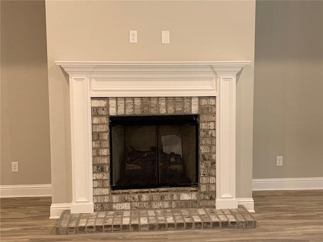 interior details with baseboards, a brick fireplace, and wood finished floors