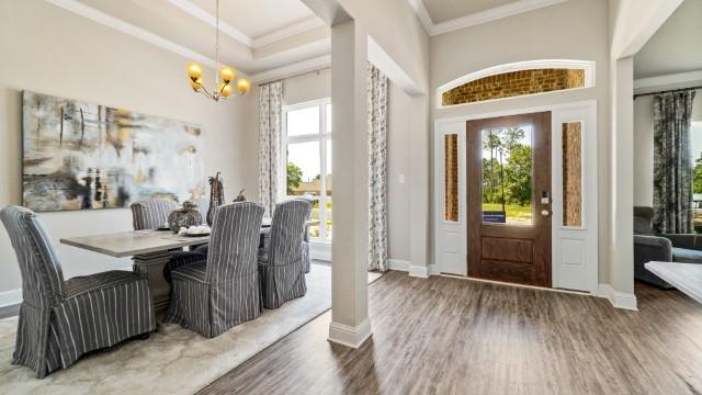 foyer with crown molding, a notable chandelier, wood finished floors, and baseboards