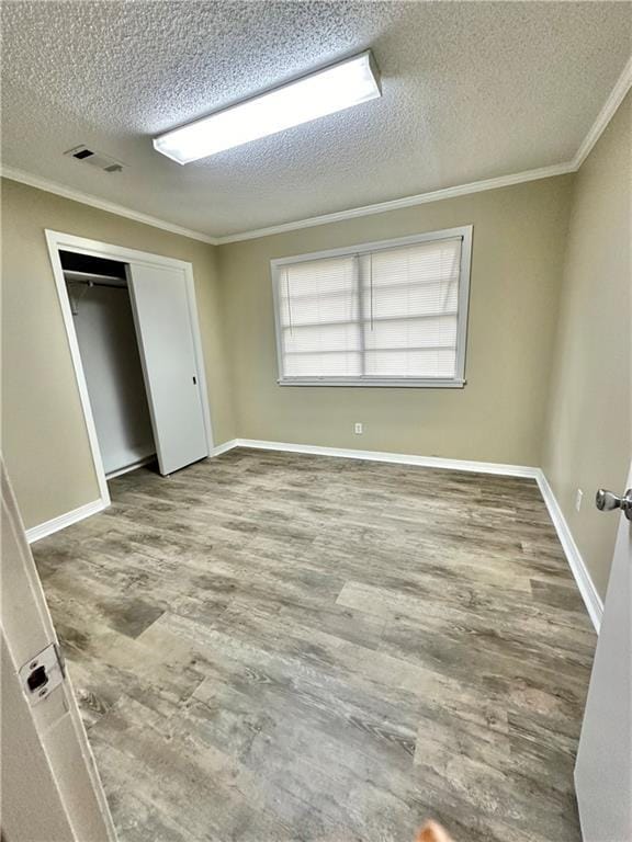 5405 Moffett Rd, Mobile, AL 36618 - unfurnished bedroom featuring a textured ceiling, visible vents, a closet, ornamental molding, and wood finished floors