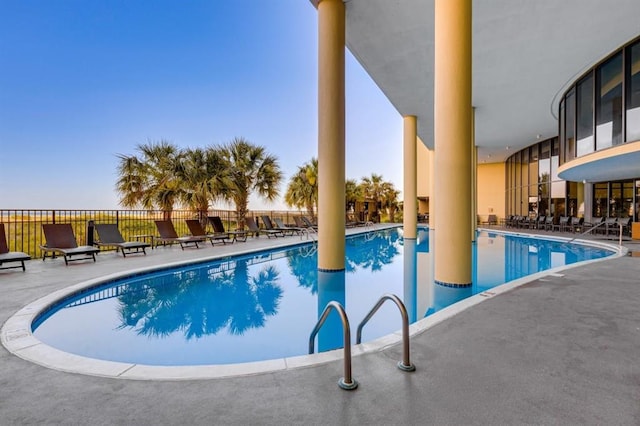 community pool with a patio and fence