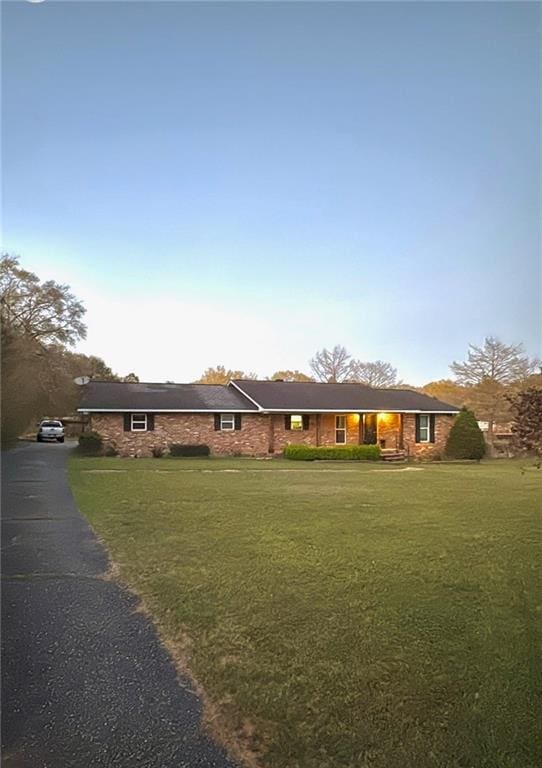 single story home featuring a front lawn and aphalt driveway