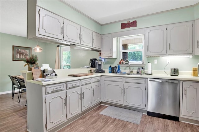 kitchen with a peninsula, stainless steel dishwasher, a healthy amount of sunlight, and a sink