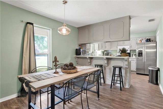 dining room with visible vents, baseboards, and wood finished floors