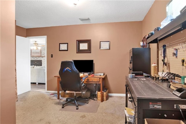 carpeted office with a textured ceiling, a workshop area, and ceiling fan
