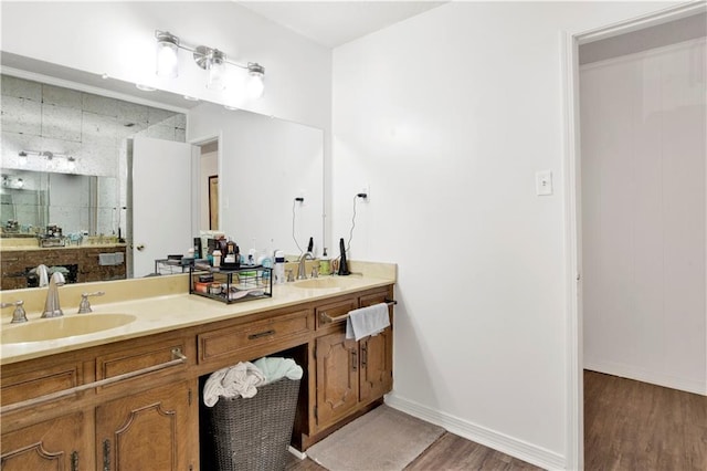 full bathroom with baseboards, wood finished floors, a sink, and double vanity