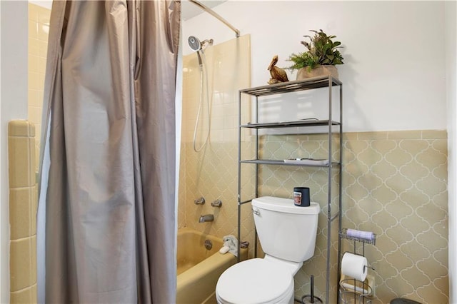 bathroom with shower / tub combo with curtain, toilet, and wainscoting