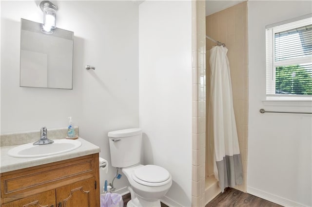 bathroom featuring a tile shower, wood finished floors, toilet, vanity, and baseboards