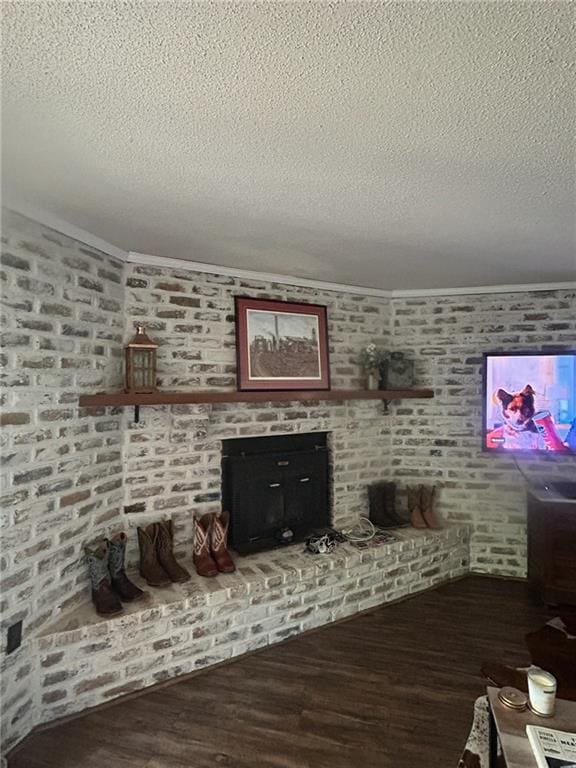 living room with brick wall, wood finished floors, a textured ceiling, and a fireplace