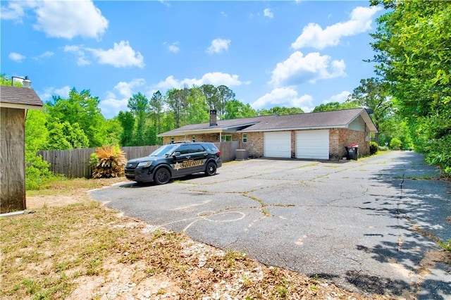 view of front of house with fence, aphalt driveway, an attached garage, and brick siding