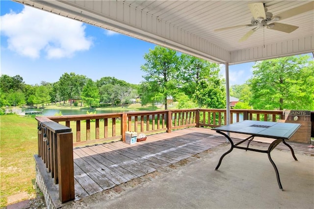 deck featuring a yard, a ceiling fan, outdoor dining space, and a water view