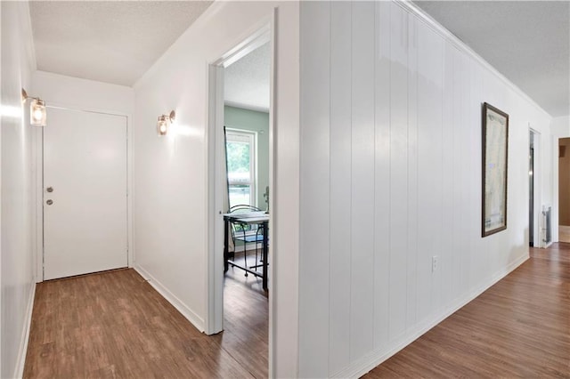 hallway with wood finished floors, baseboards, and ornamental molding