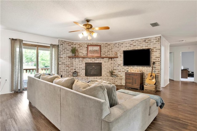 living room featuring visible vents, a textured ceiling, ceiling fan, and dark wood finished floors