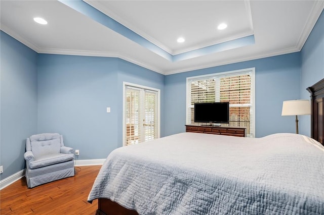 bedroom with crown molding, hardwood / wood-style flooring, and a tray ceiling