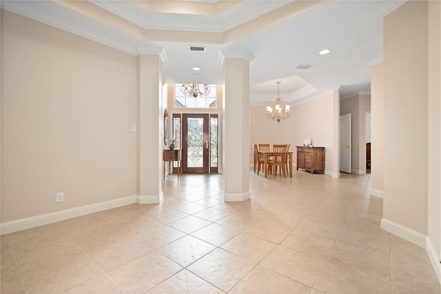 hall featuring light tile patterned flooring, crown molding, a chandelier, a tray ceiling, and decorative columns