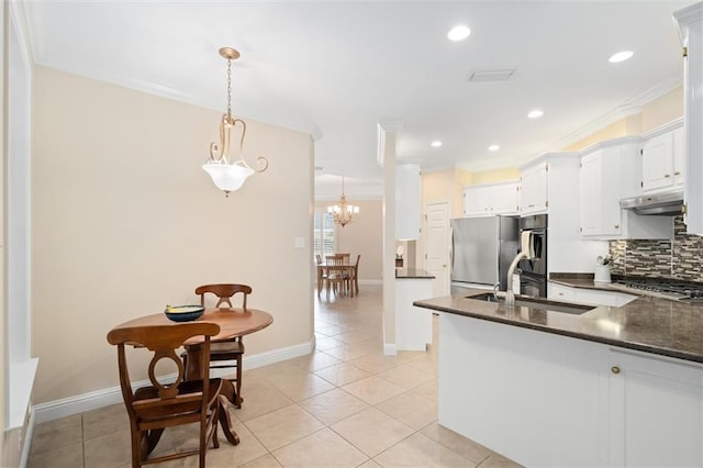 kitchen with sink, appliances with stainless steel finishes, decorative backsplash, white cabinets, and decorative light fixtures