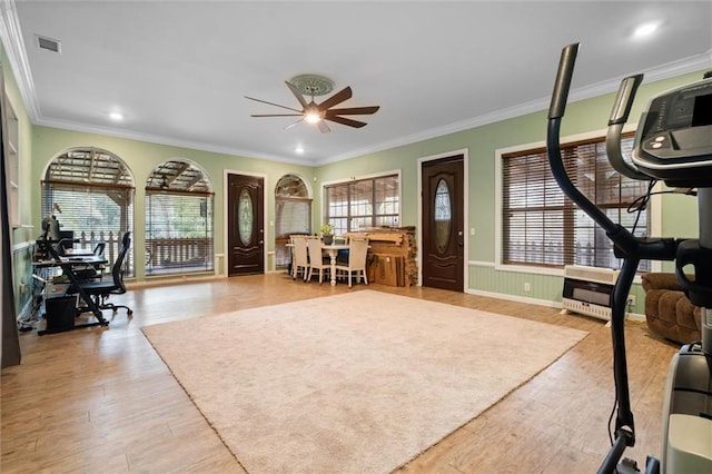 exercise area featuring ornamental molding, heating unit, ceiling fan, and light hardwood / wood-style floors