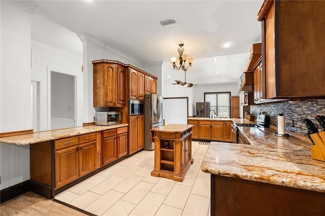 kitchen featuring stainless steel appliances, a kitchen island, light stone counters, and kitchen peninsula