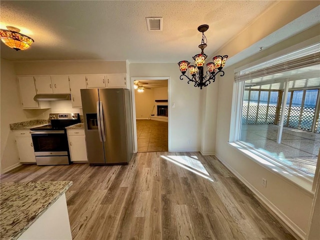 kitchen with hanging light fixtures, stainless steel appliances, white cabinets, a textured ceiling, and light hardwood / wood-style floors