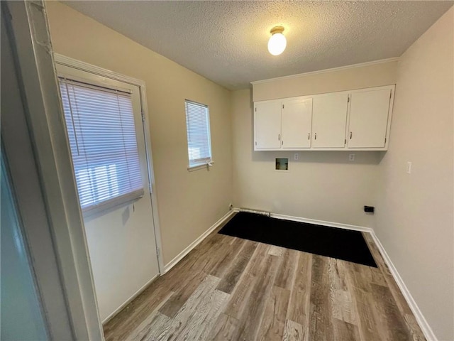 laundry area with a textured ceiling, washer hookup, cabinet space, and wood finished floors