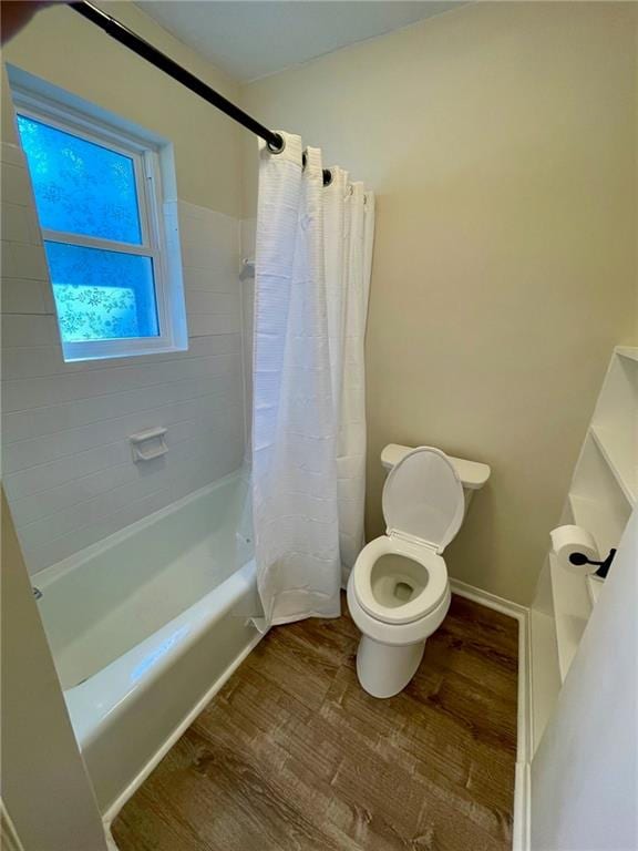 bathroom featuring hardwood / wood-style floors, shower / tub combo with curtain, and toilet